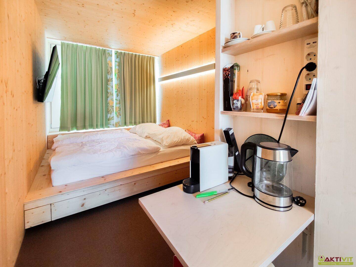 Schlafbereich mit integriertem Bettrahmen aus Holz, Regalen und einem Fenster mit Vorhängen.