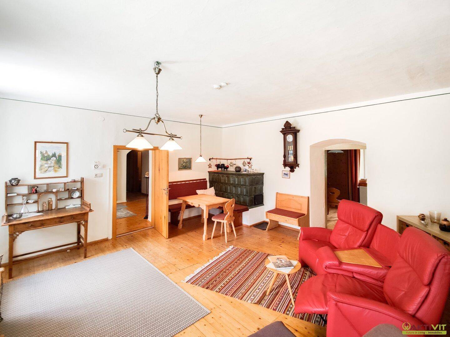 Traditionelles Wohnzimmer mit Kachelofen, Holzboden und rustikalen Möbeln, ideal für gemütliche Abende.