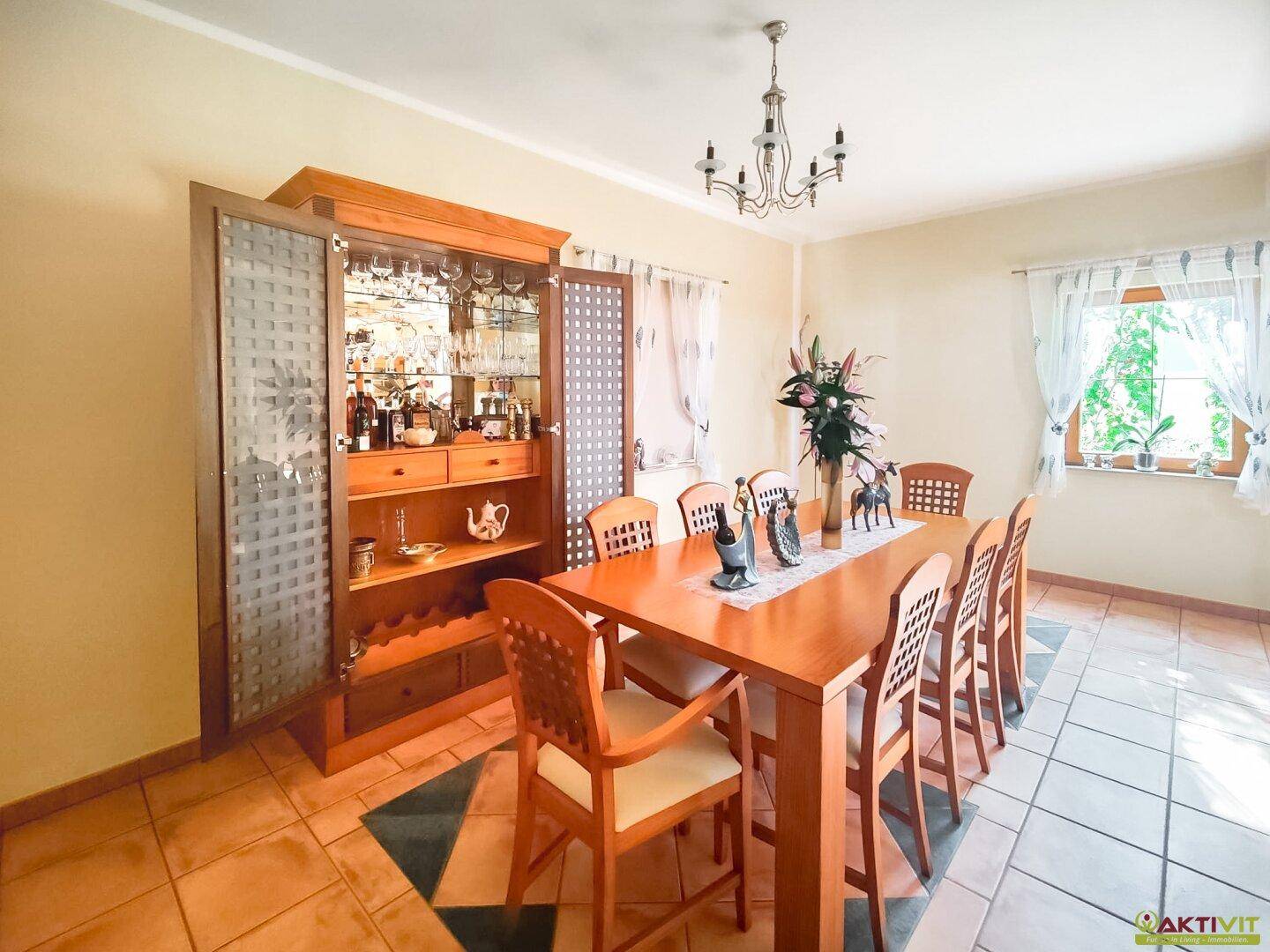 Klassischer Essbereich mit großem Holztisch, passenden Stühlen und einem eleganten Vitrinenschrank.