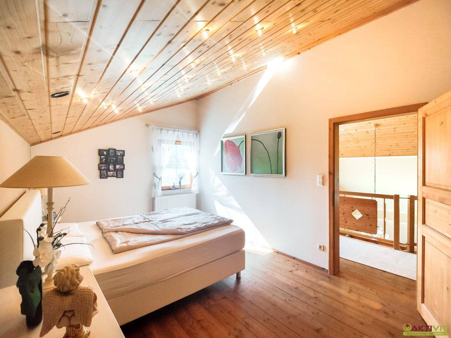 Gemütliches Schlafzimmer mit Holzdielenboden, Dachschräge und einem Fenster für natürliches Licht.