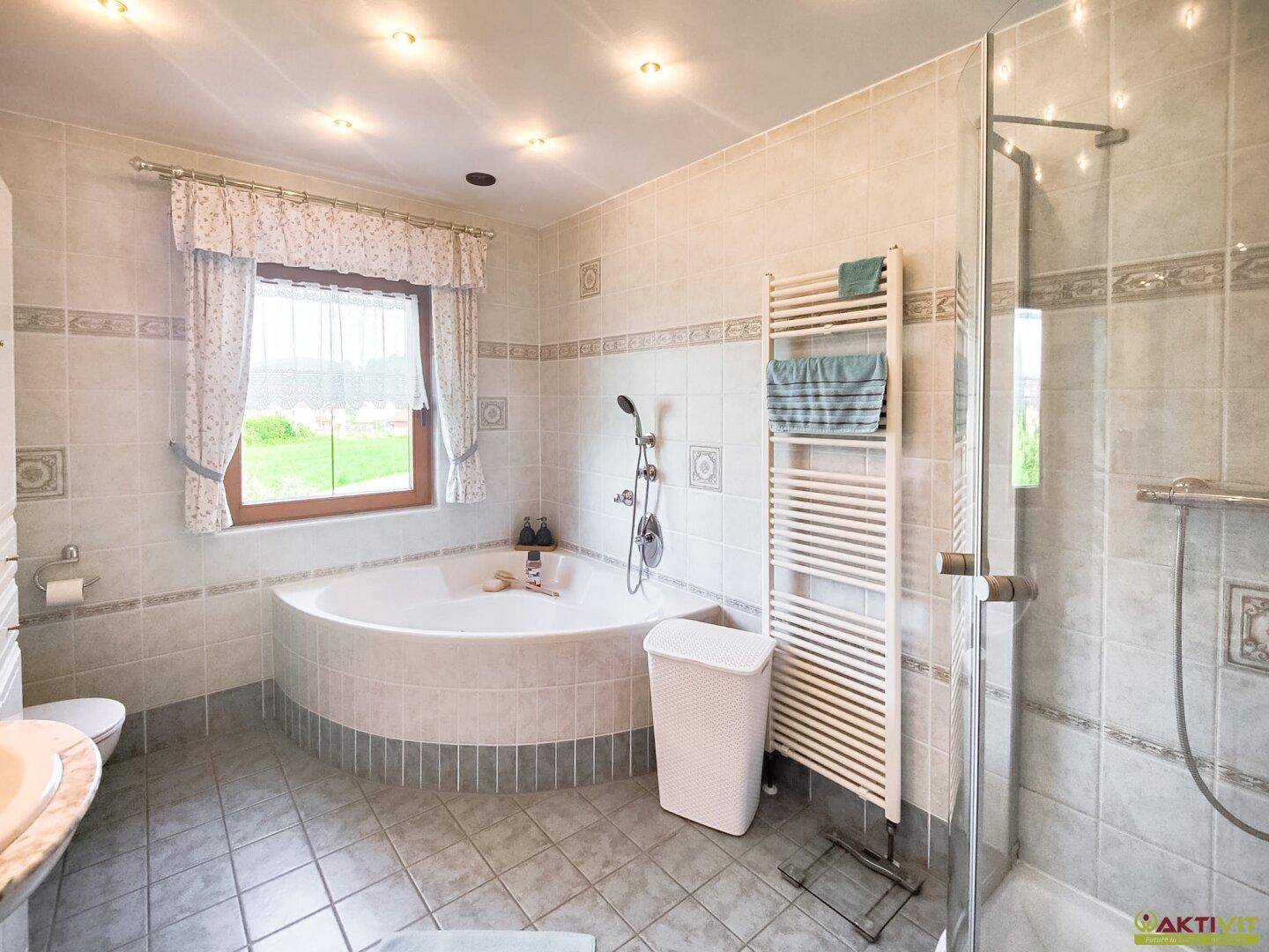 Geräumiges Badezimmer mit Eckbadewanne, separater Dusche und beheiztem Handtuchhalter.