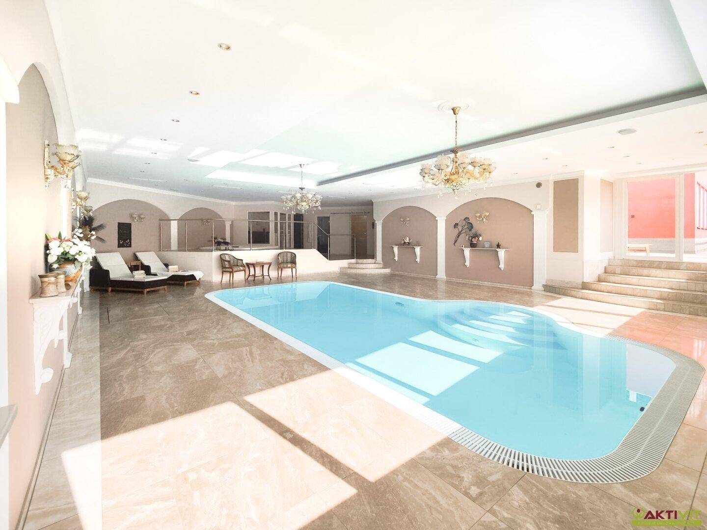 Eleganter Innenpoolbereich mit viel Tageslicht, Marmorfliesen und stilvollen Sitzgelegenheiten.