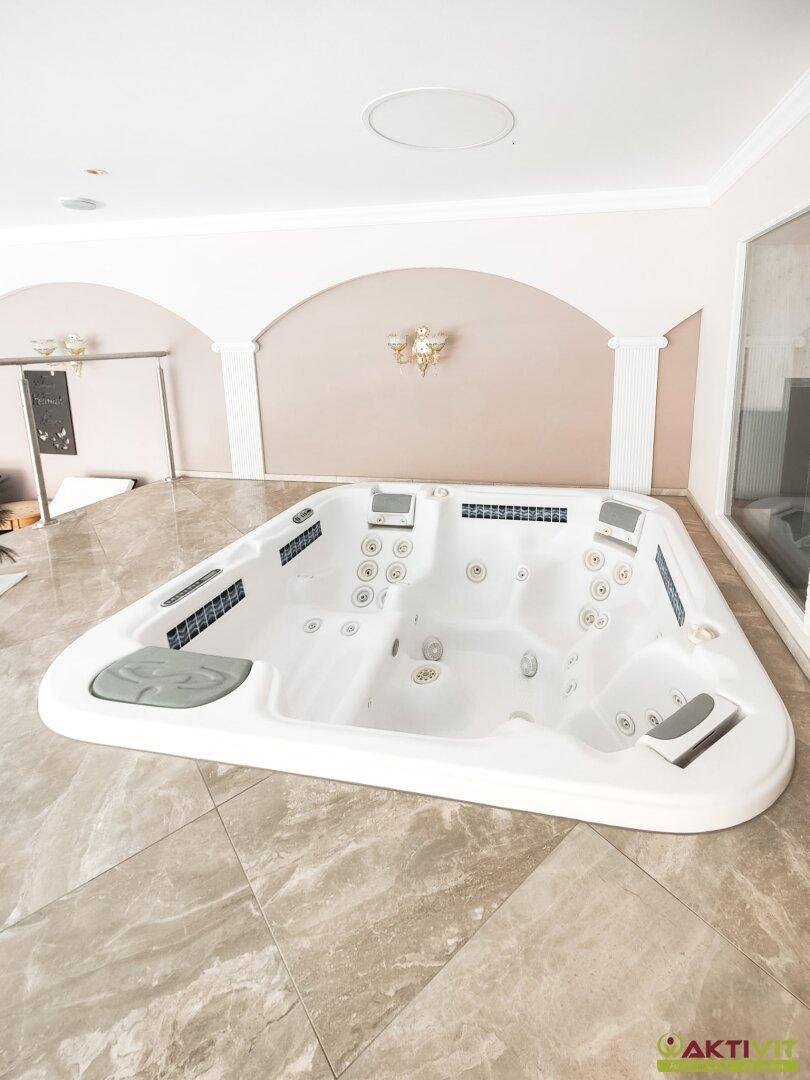 Geräumiger Whirlpool mit mehreren Düsen und Sitzplätzen, umgeben von eleganten Marmorfliesen.
