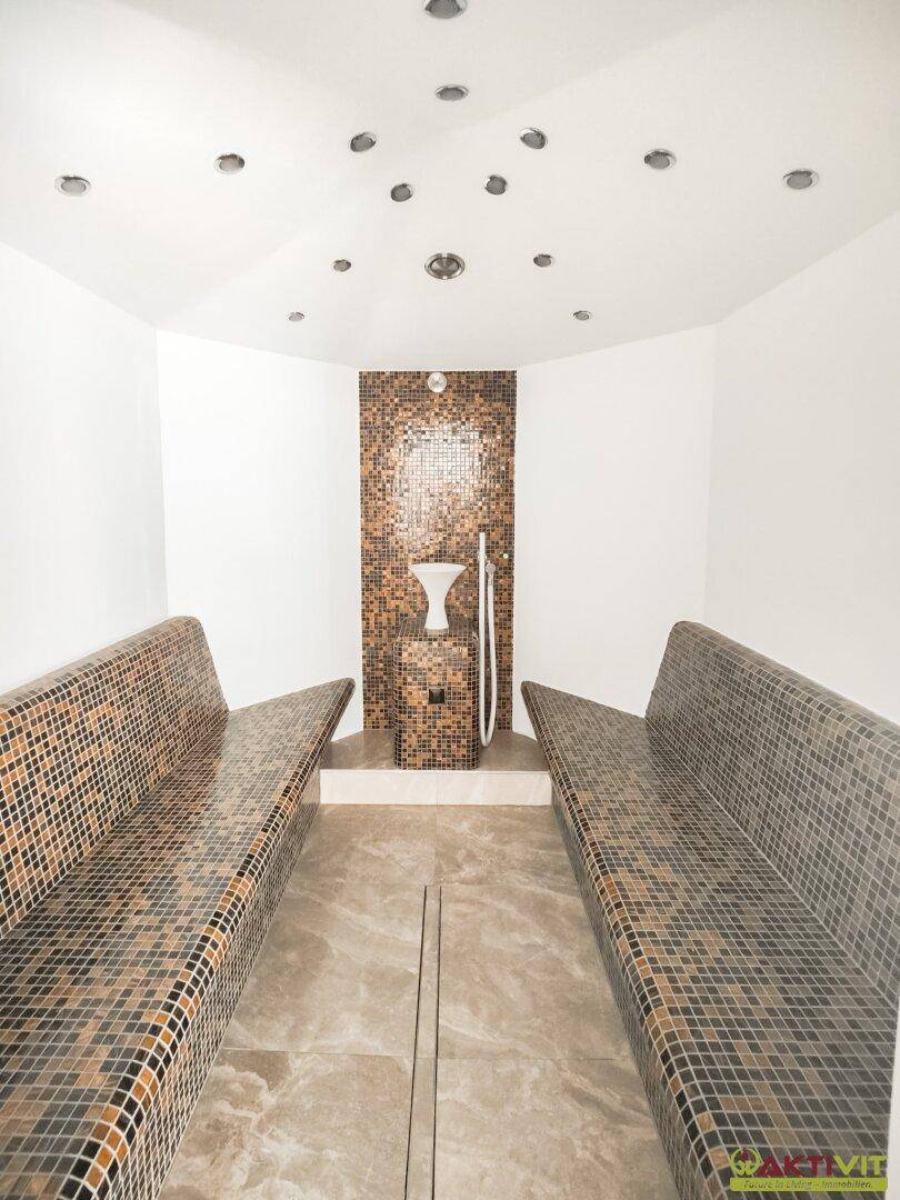 Entspannender Dampfbadbereich mit Mosaikfliesen und ergonomischen Liegen für Wellness.