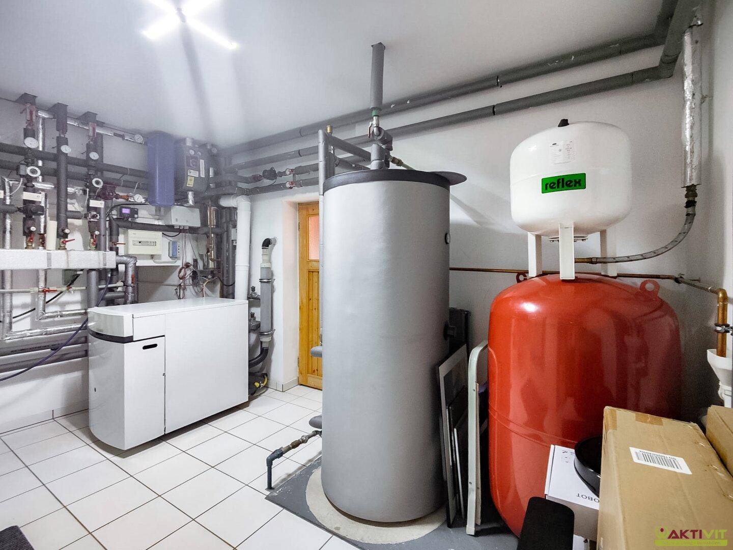 Technikraum mit Heizungsanlage, Warmwasserspeicher und verschiedenen Installationen.