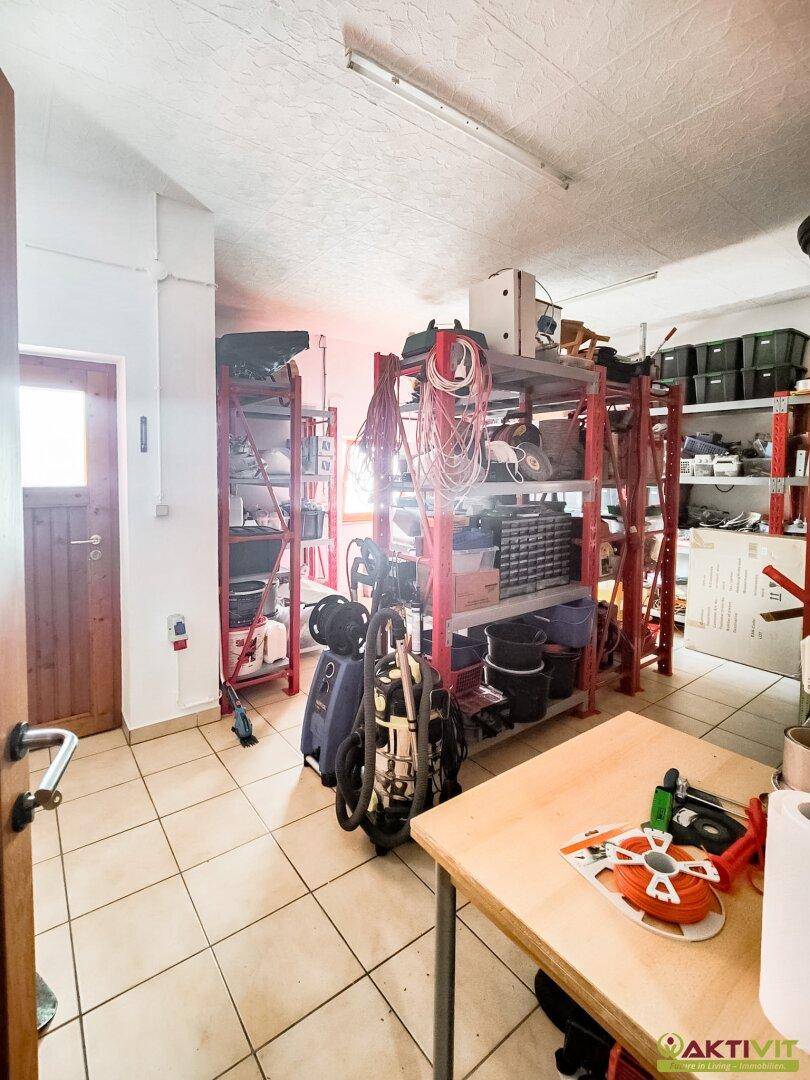 Praktischer Abstellraum mit Fliesenboden, Metallregalen und verschiedenen Werkzeugen und Geräten.