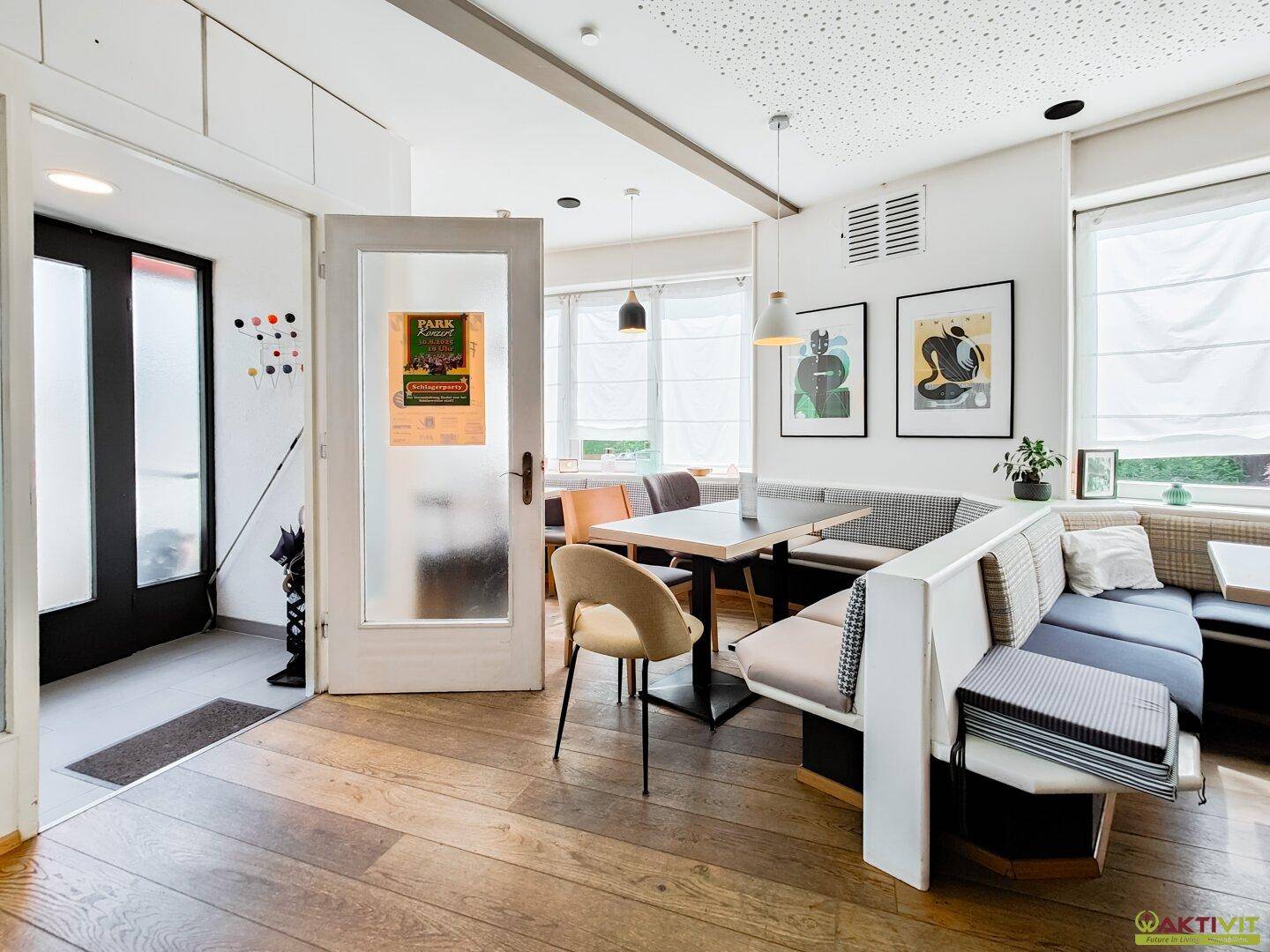 Heller Innenraum mit Holzboden und bequemen Sitzbänken, ideal für ein Café oder Restaurant.