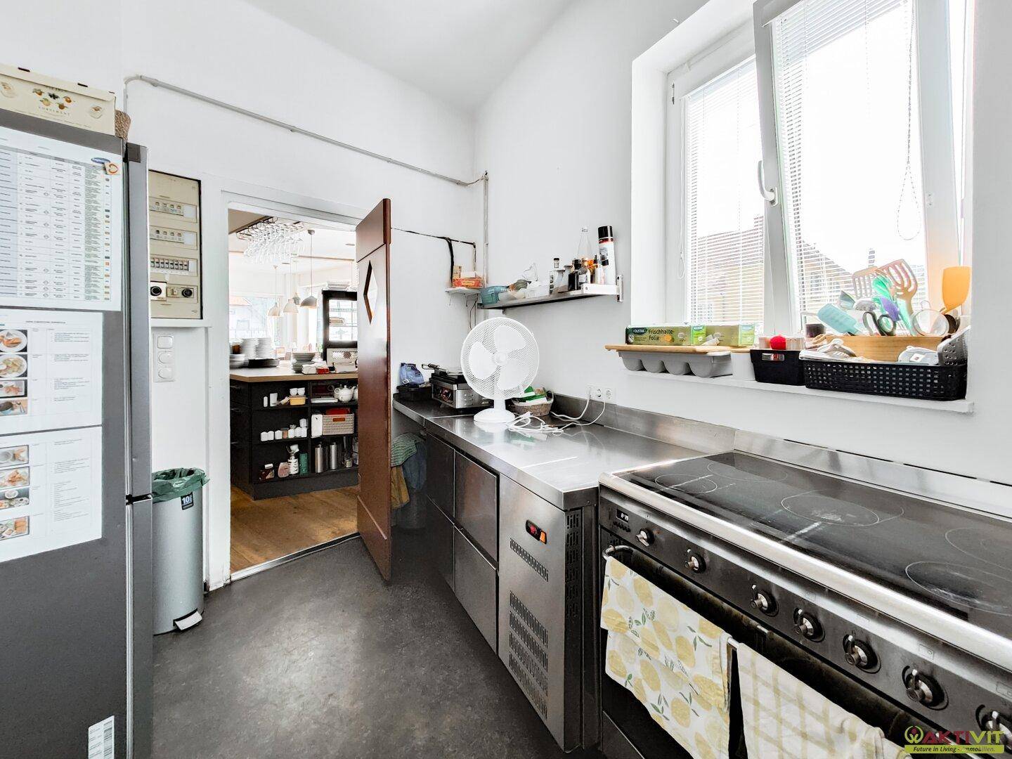 Professionelle Edelstahlküche mit großem Herd und Fenster, optimiert für den Gastronomiebedarf.