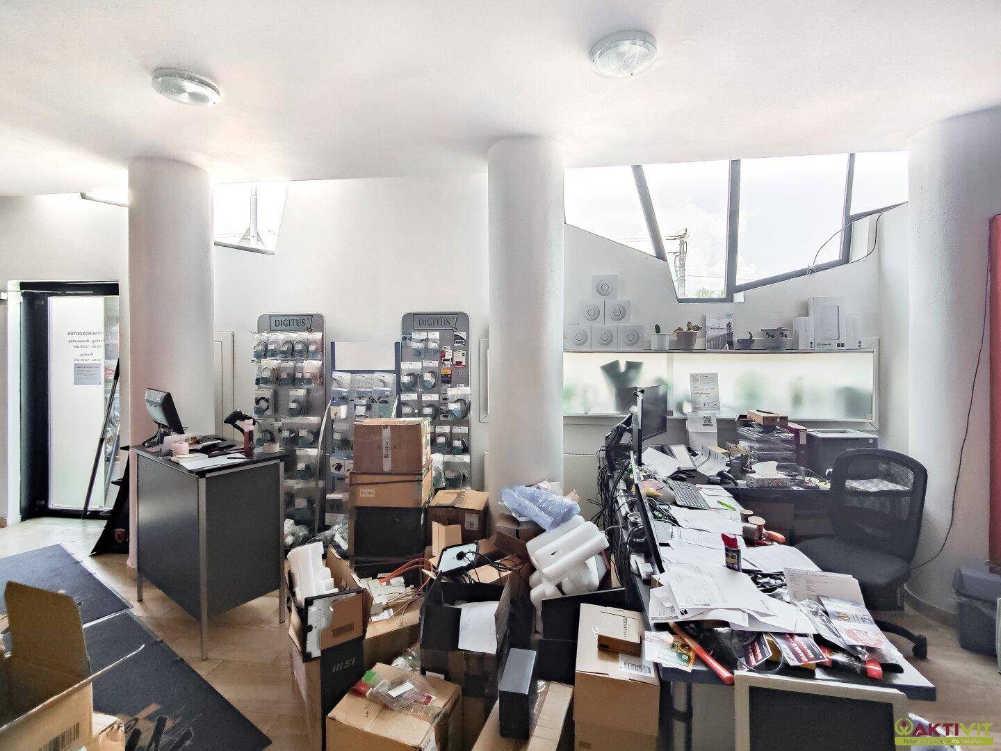 Helles Büro mit großen Fenstern, mehreren Arbeitsplätzen und Regalen voller Produkte.