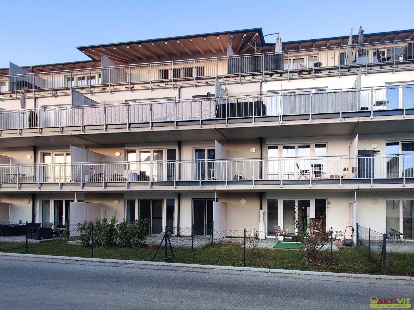 Moderne Wohnanlage mit mehreren Balkonen und Terrassen, umgeben von Grünflächen.