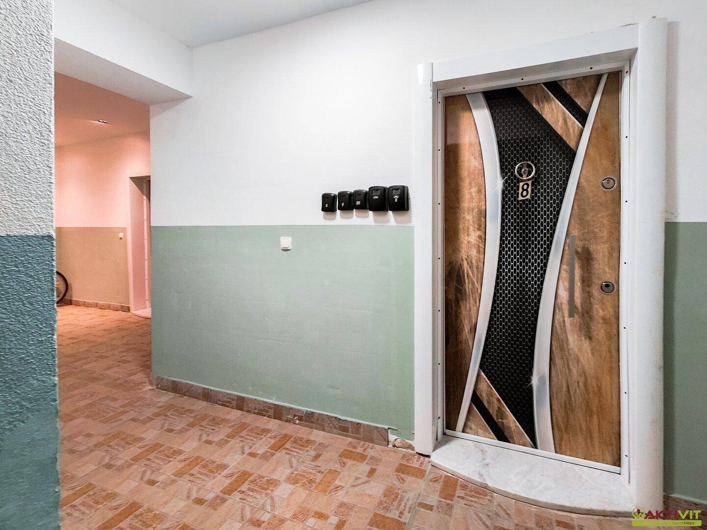 Eingangsbereich eines Flurs mit einer modernen Wohnungstür und Briefkästen an der Wand.