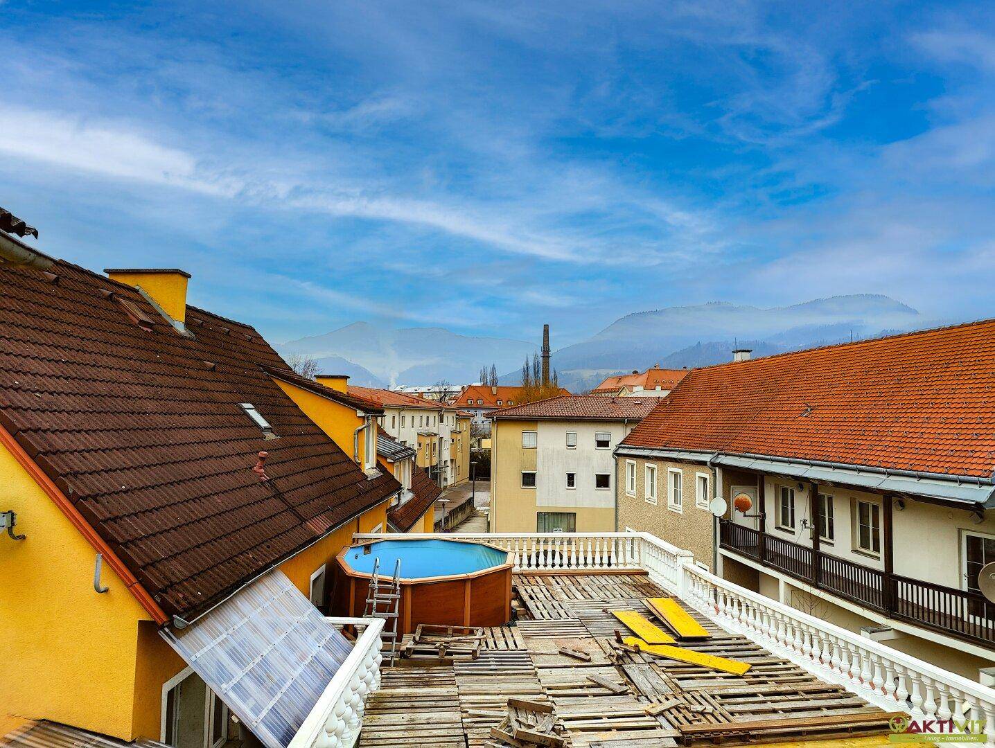 Große Dachterrasse mit einem Aufstellpool und weitem Blick auf die umliegende Berglandschaft.