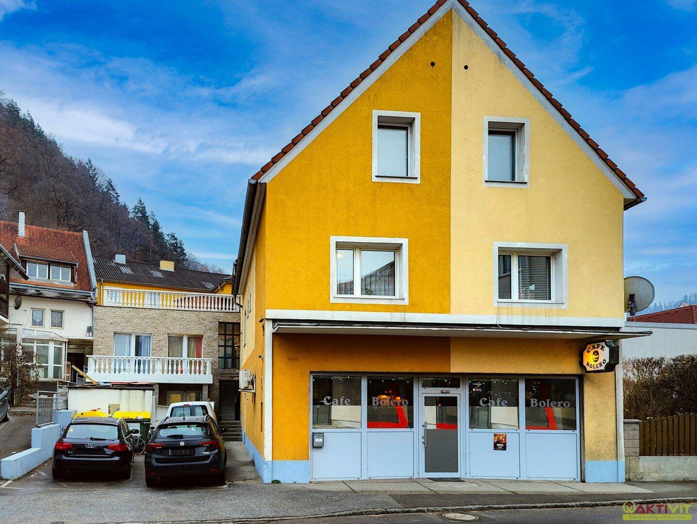 Vorderansicht des gelben Gebäudes mit einem Café im Erdgeschoss und Fenstern in den oberen Etagen.