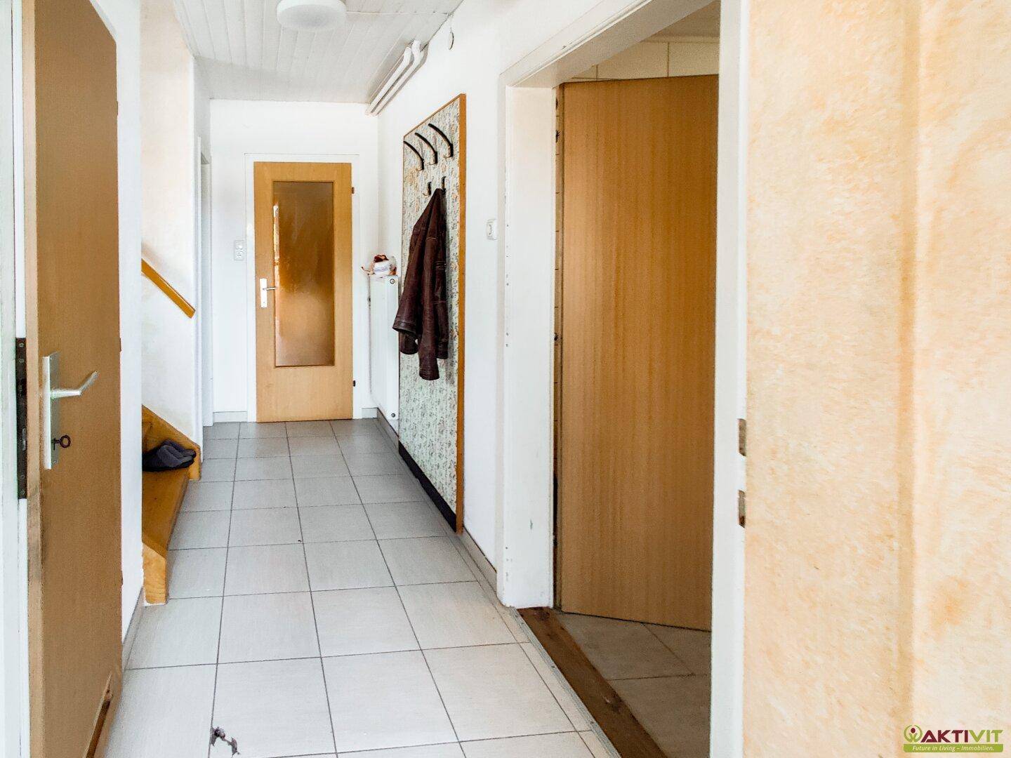 Heller Flur mit Fliesenboden, Garderobe und Zugang zu weiteren Räumen.