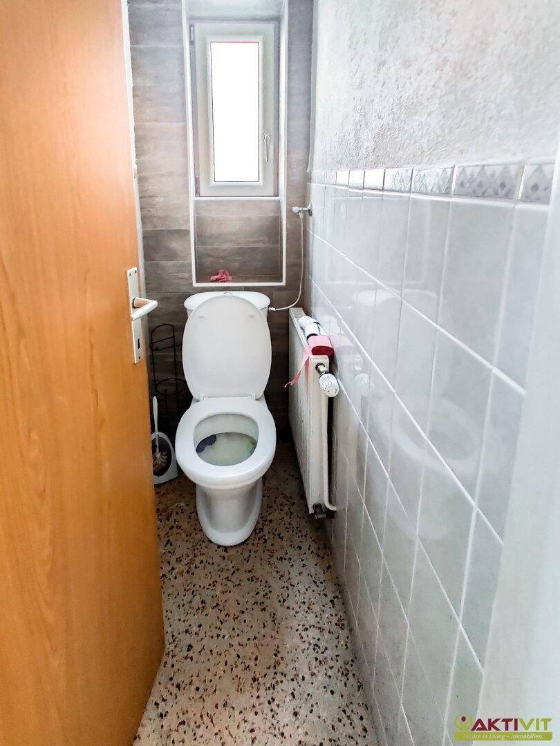 Kleines Gäste-WC mit Fenster, Toilette und Heizkörper.