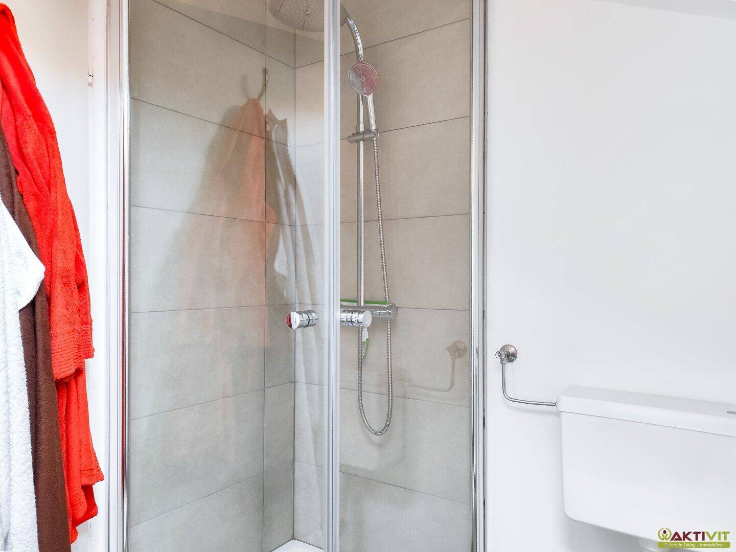 Modernes Badezimmer mit Duschkabine und hellen Fliesen, funktional und sauber.