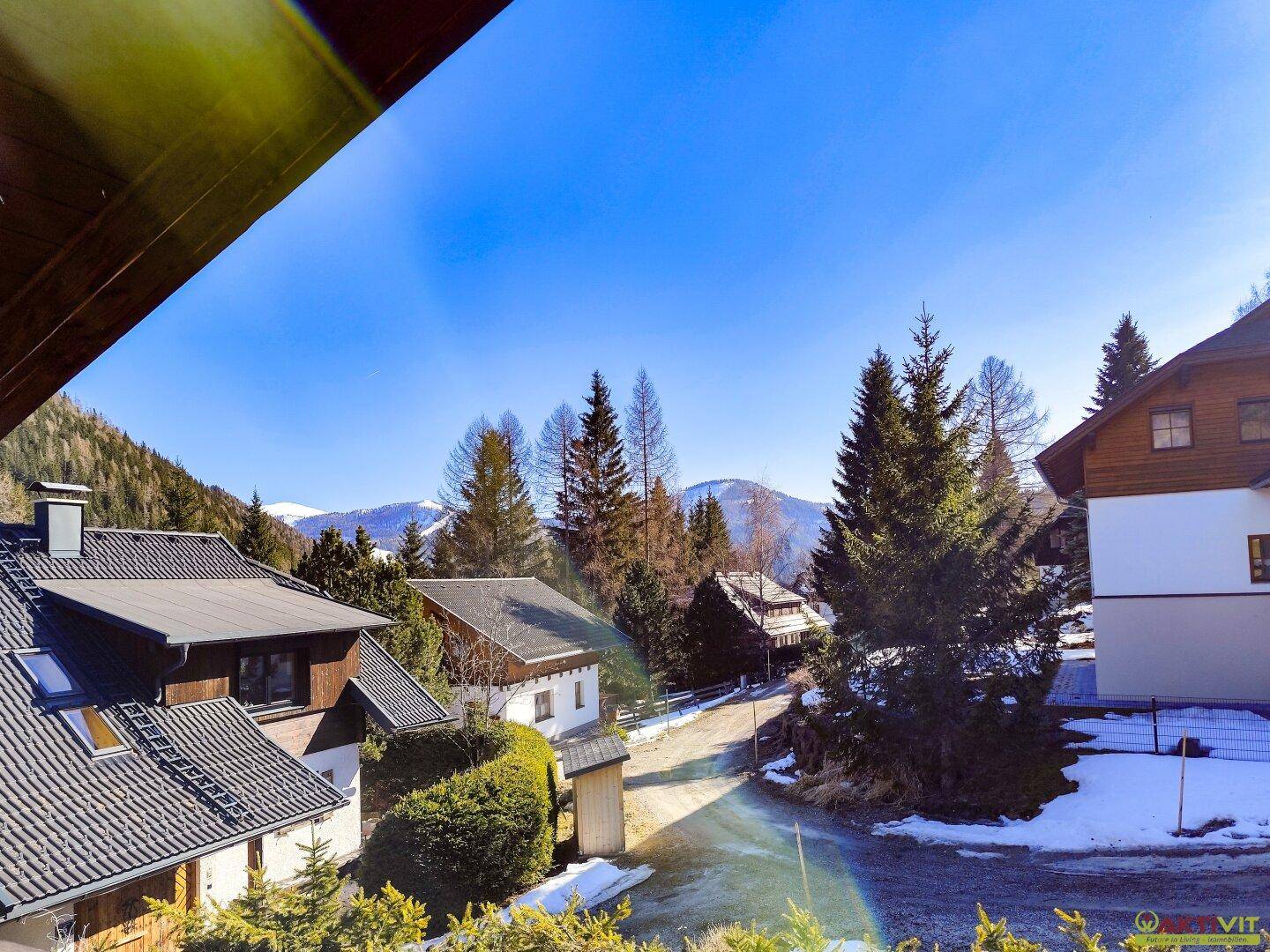 Panoramablick auf die verschneite Berglandschaft und die umliegenden Häuser.