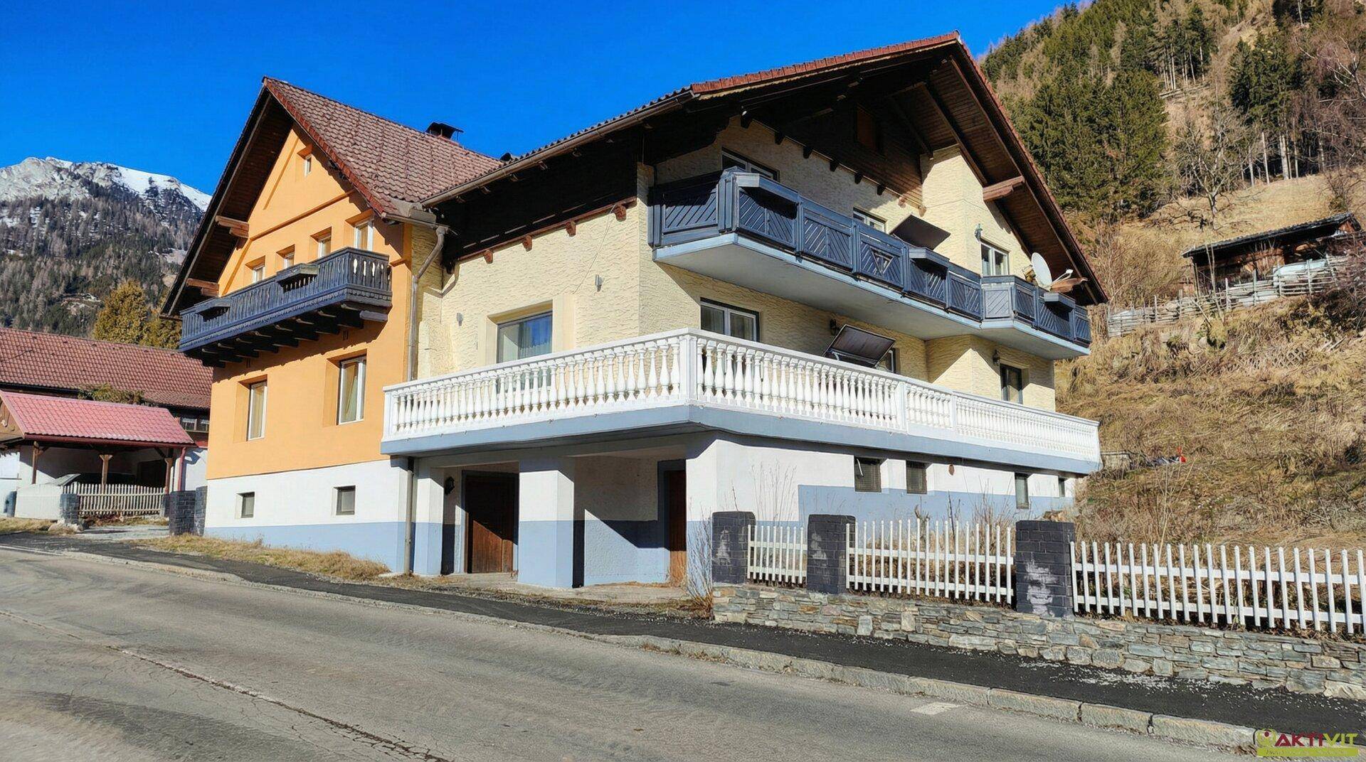 Seitenansicht des Hauses mit Balkonen und Blick auf die umliegende Berglandschaft.