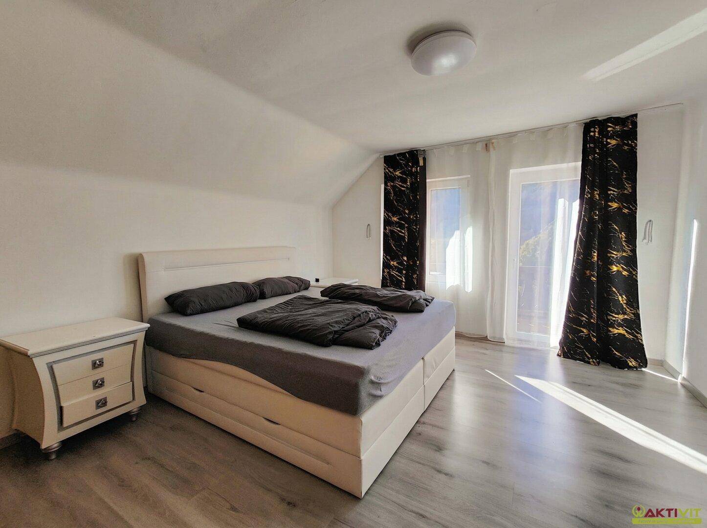 Lichtdurchflutetes Schlafzimmer mit Doppelbett, Nachttisch und Balkonzugang.
