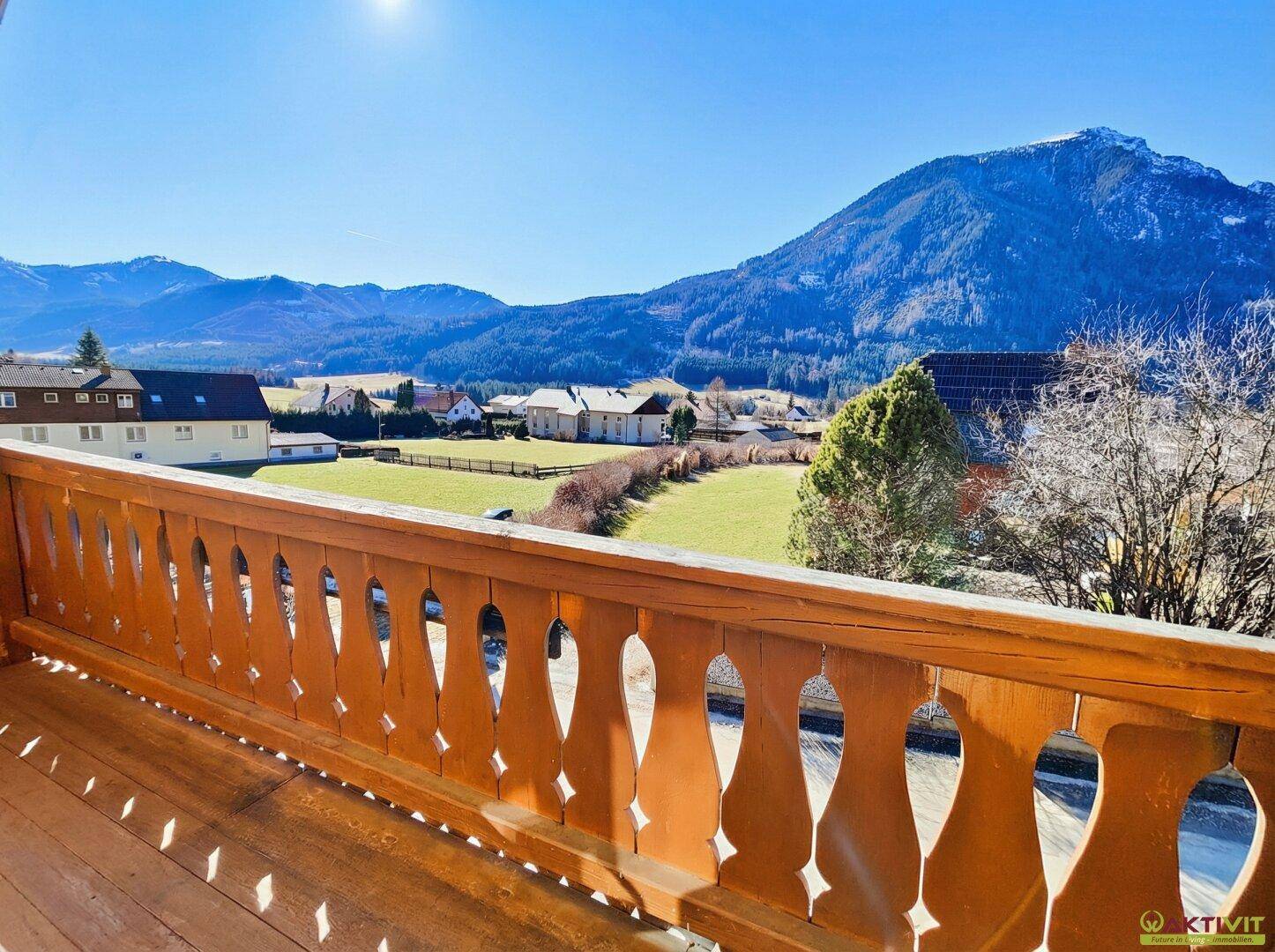 Geräumiger Holzbalkon mit traditionellem Geländer und Panoramablick auf die Berge.