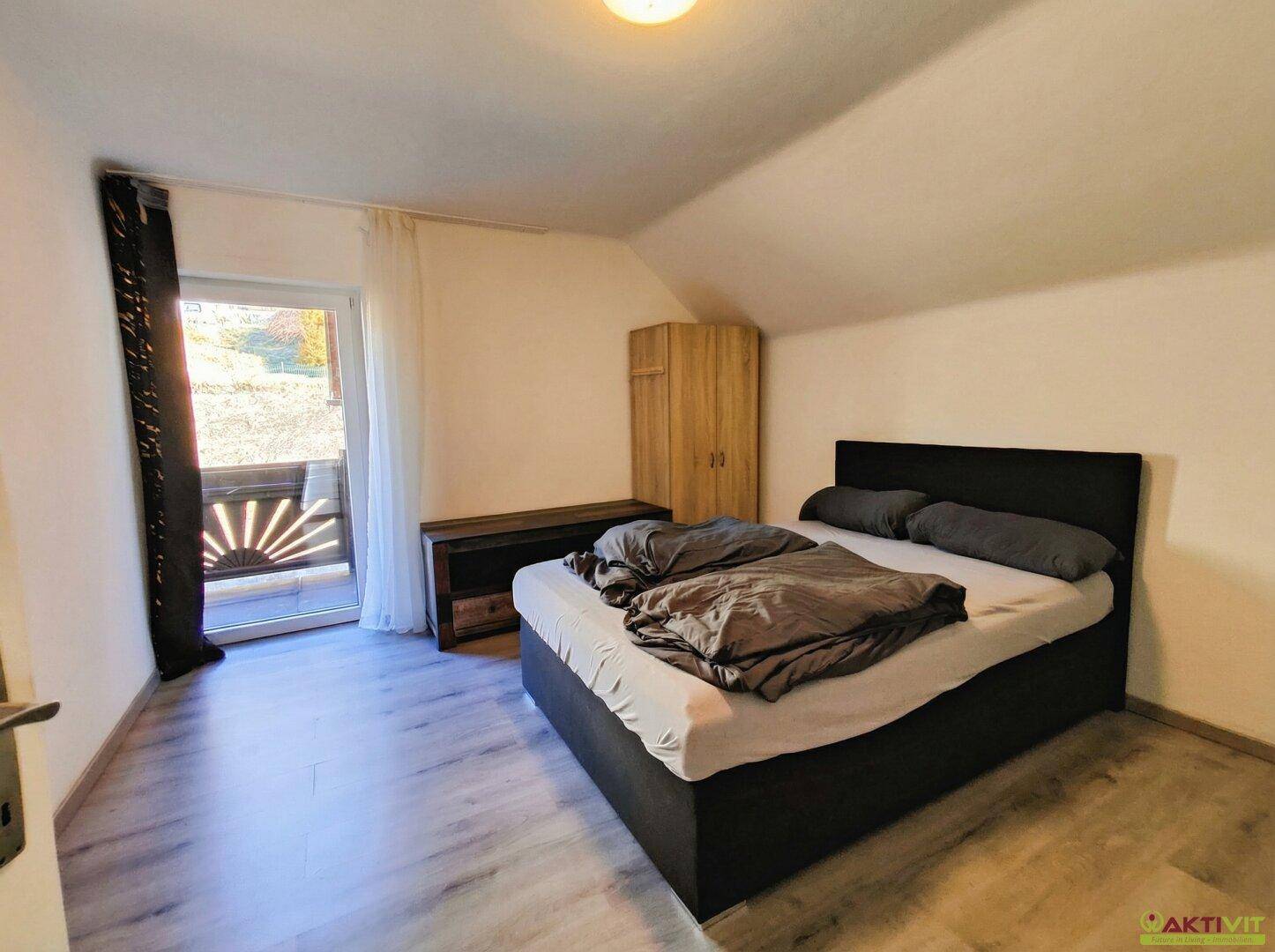 Schlafzimmer mit Doppelbett, Kleiderschrank und Zugang zu einem Balkon.