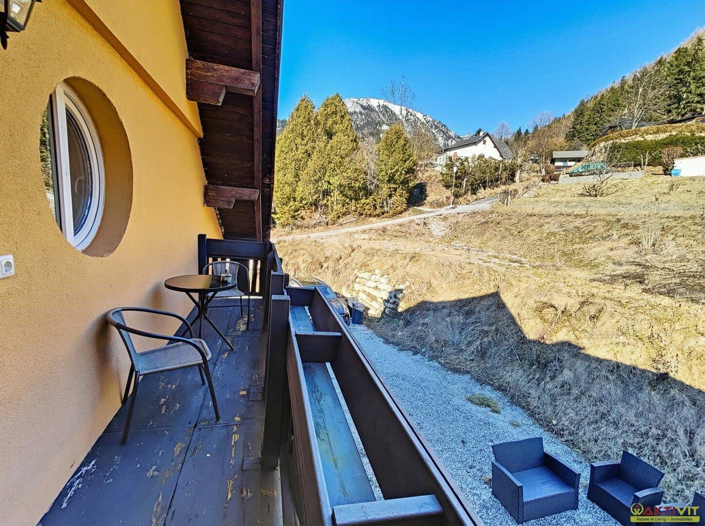 Kleiner Balkon mit Sitzgelegenheiten und Blick auf die bewaldeten Hügel.
