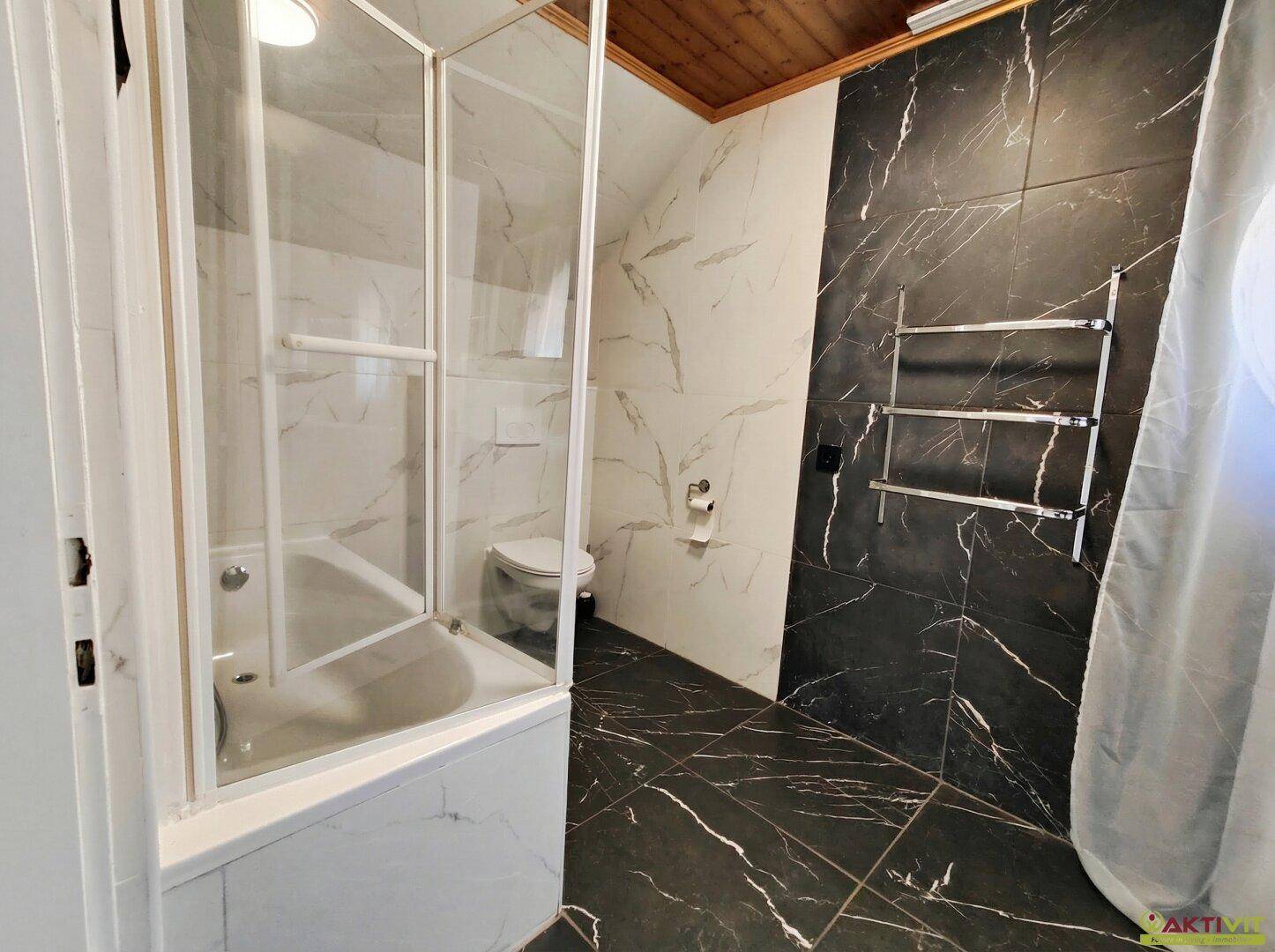 Modernes Badezimmer mit Badewanne, Dusche und eleganten Marmorfliesen.
