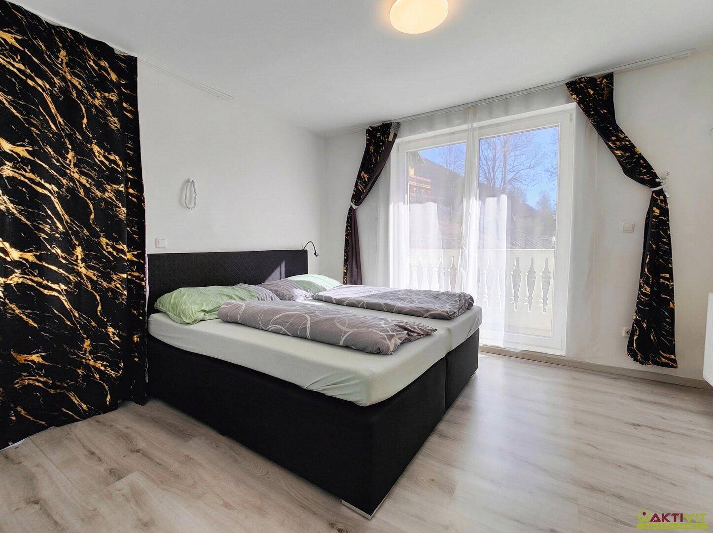 Lichtdurchflutetes Schlafzimmer mit Doppelbett und Zugang zu einem Balkon.