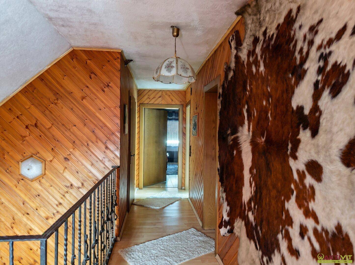 Flur mit Holzverkleidung, Holzboden und dekorativem Kuhfell an der Wand.