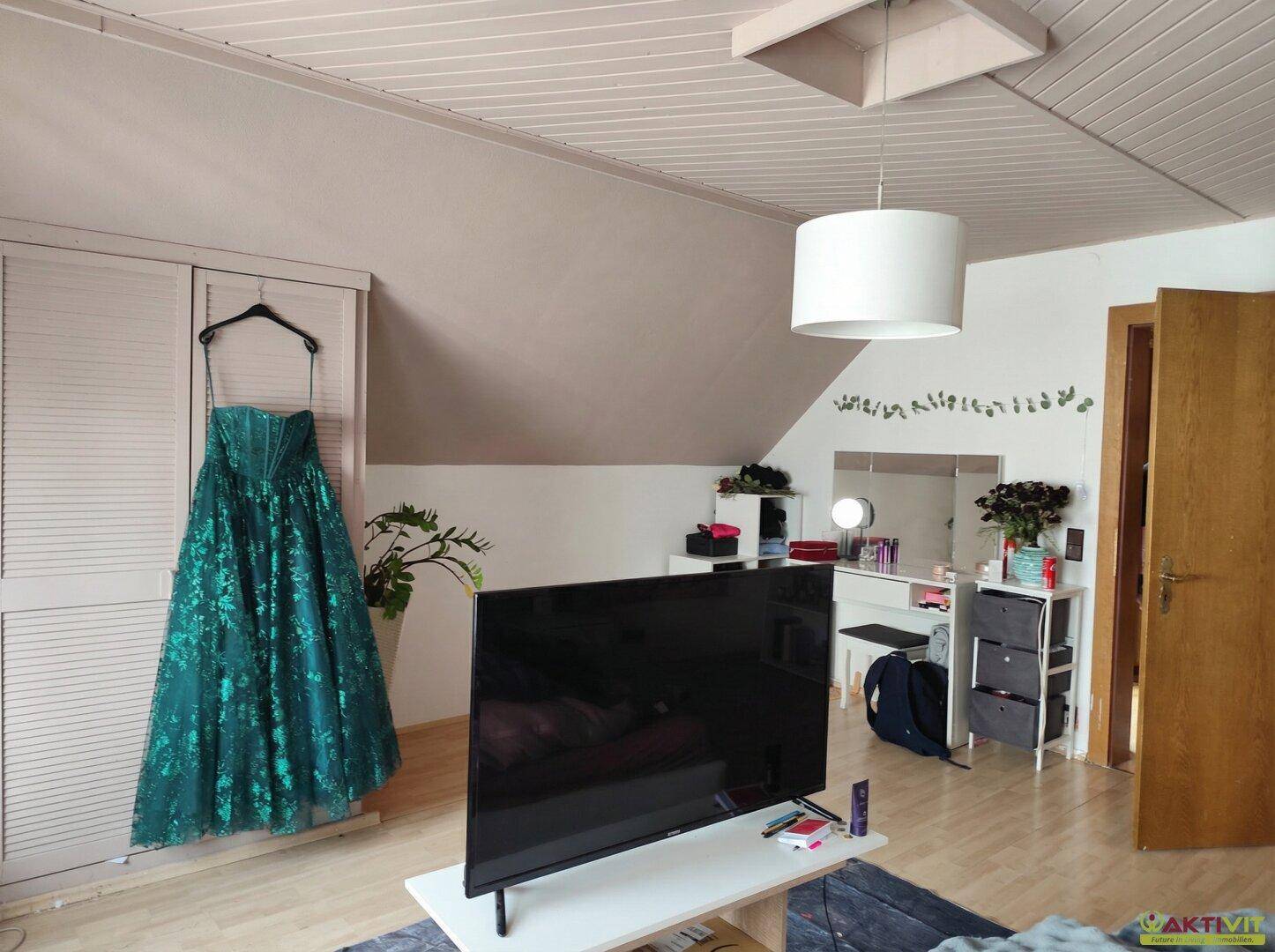 Schlafzimmer im Dachgeschoss mit Dachschräge, Fernseher und Schminktisch.