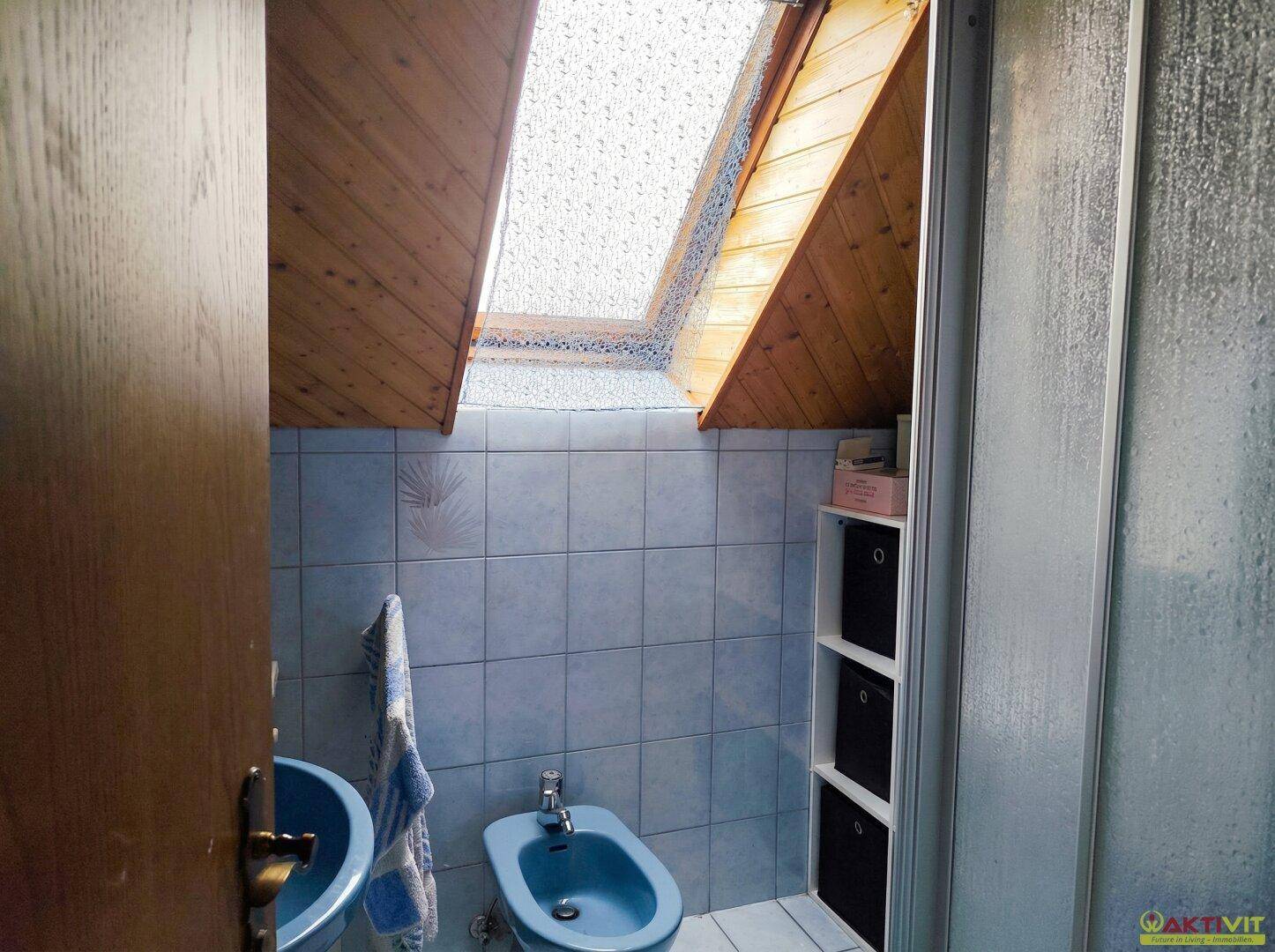 Badezimmer mit Dusche, Bidet, Waschbecken und Dachfenster.