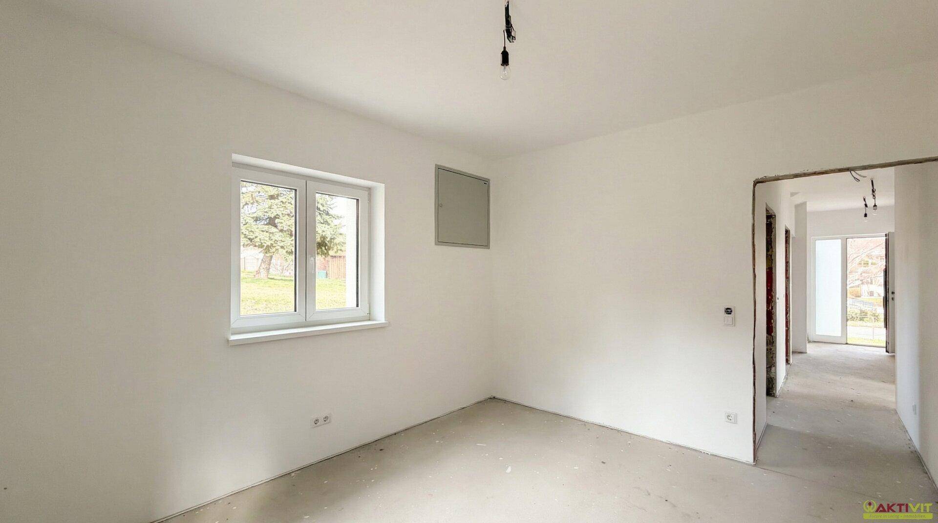 Unfertiger Raum mit Fenster und Zugang zum Flur, ideal für Schlafzimmer oder Büro.