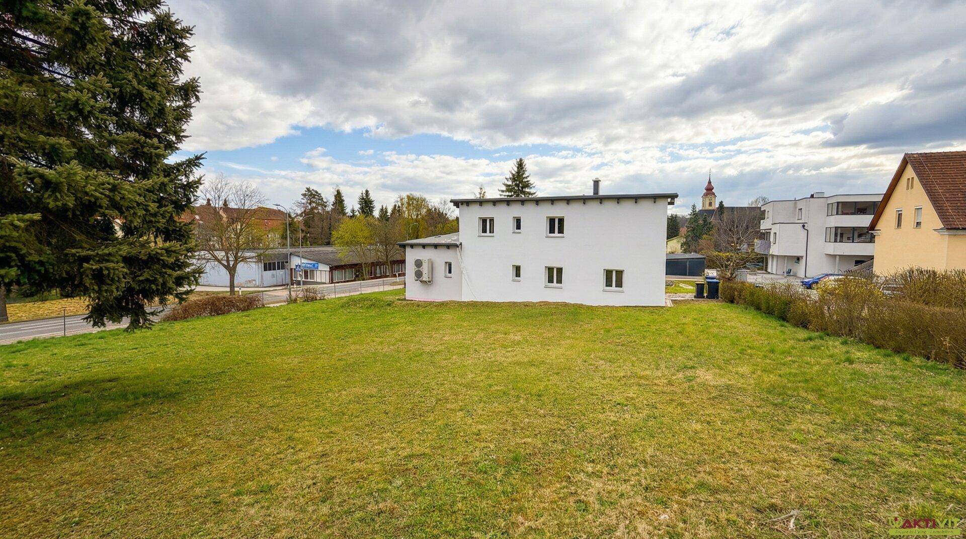 Großes grünes Grundstück mit Blick auf die Nachbarschaft und eine Kirche im Hintergrund.