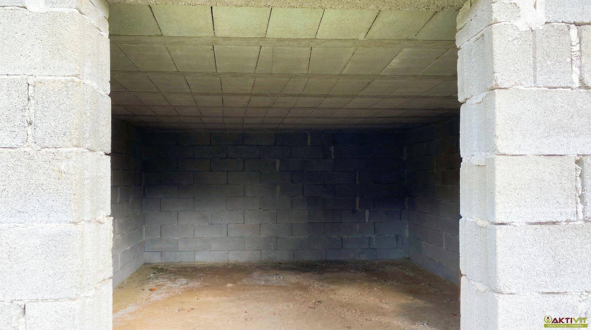Unfertiger Innenraum mit Wänden aus Betonblöcken und einer einfachen Deckenkonstruktion.