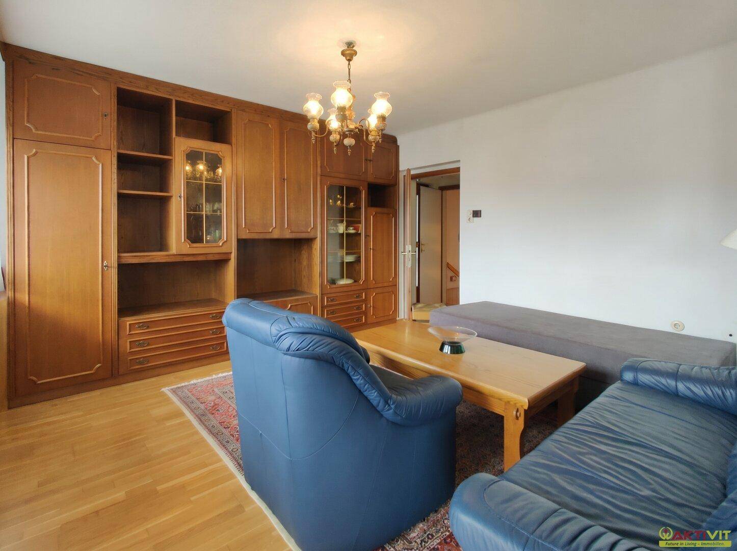 Wohnzimmer mit großer Holzschrankwand, bequemen Sofas und klassischer Beleuchtung.
