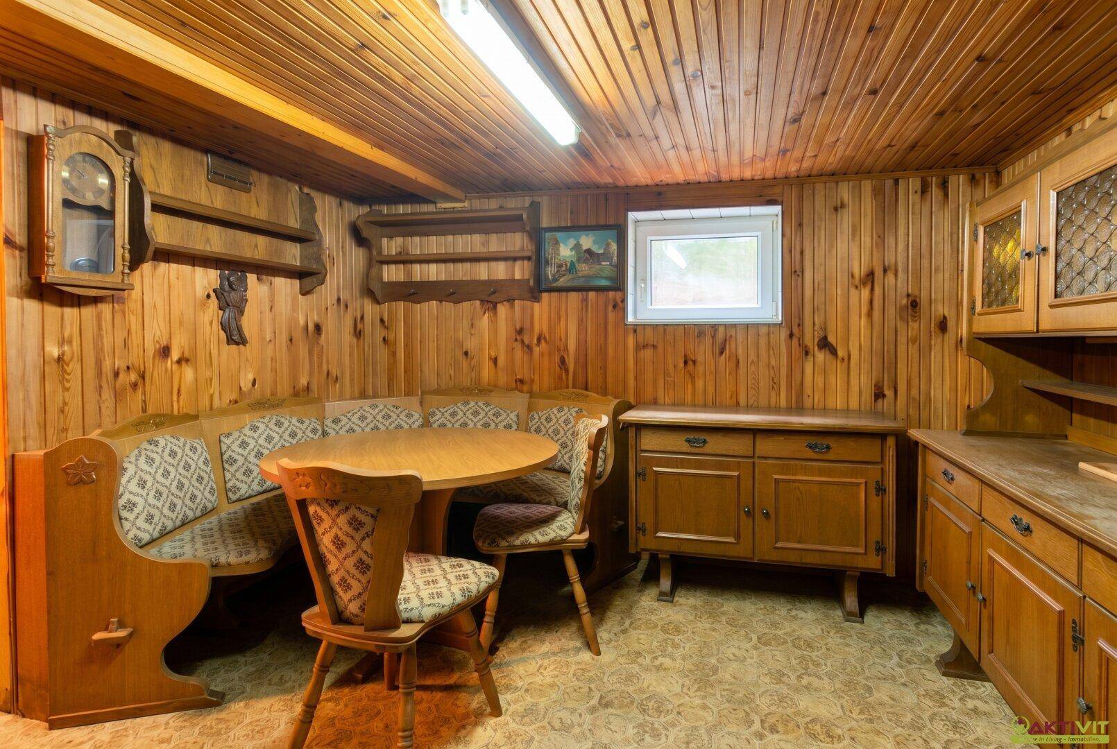Rustikaler Kellerraum mit Holzvertäfelung, Sitzecke und traditionellen Holzmöbeln.
