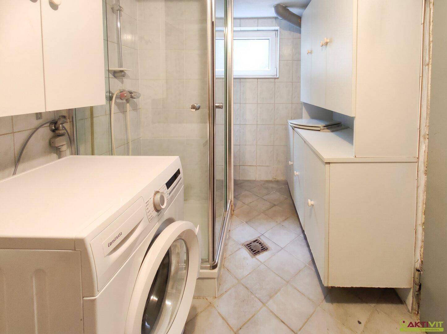 Waschküche im Keller mit Waschmaschine, Duschkabine und praktischen Schränken.
