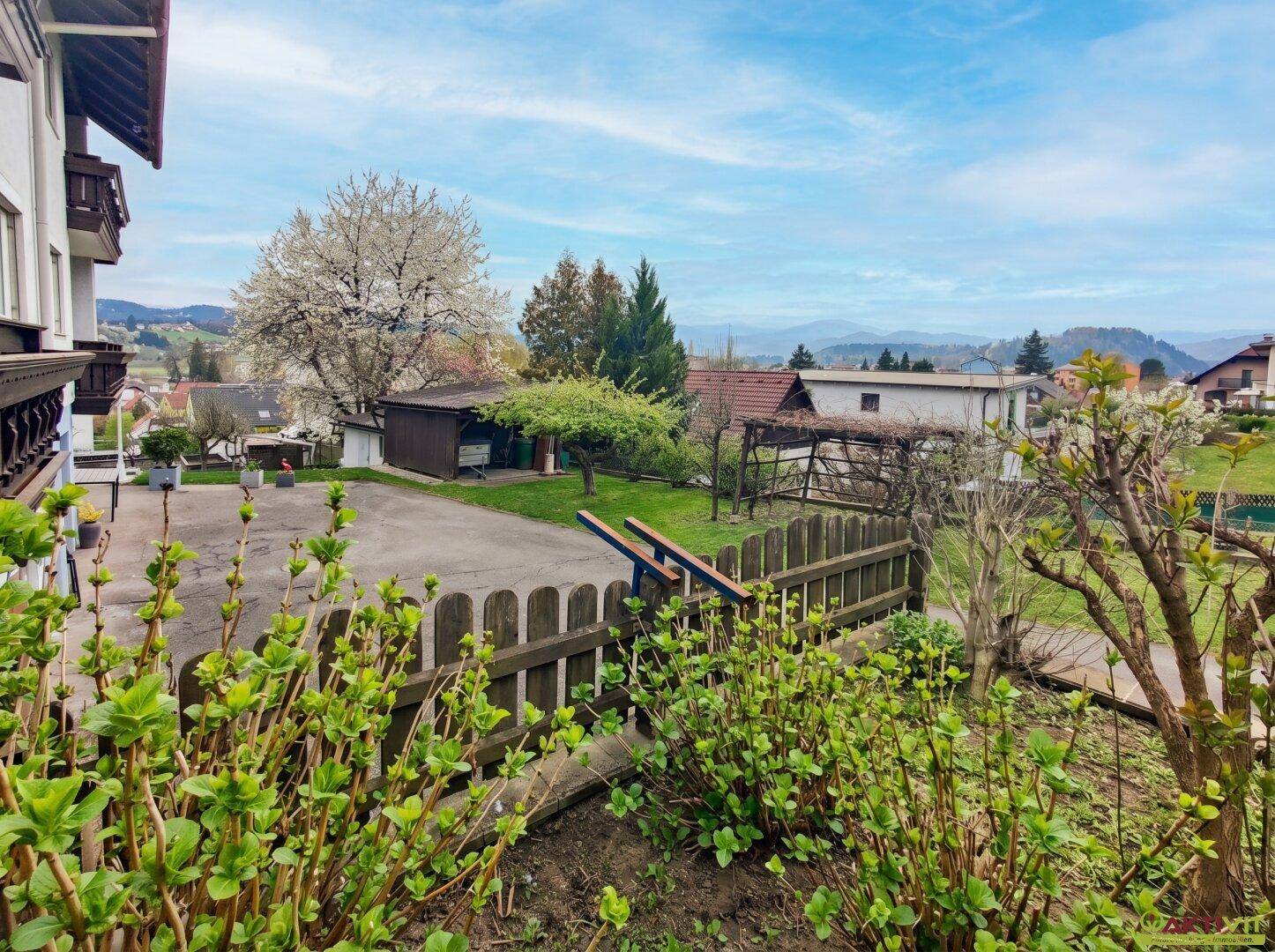 Gartenbereich mit Zaun und Blick auf die umliegende Landschaft und Berge.