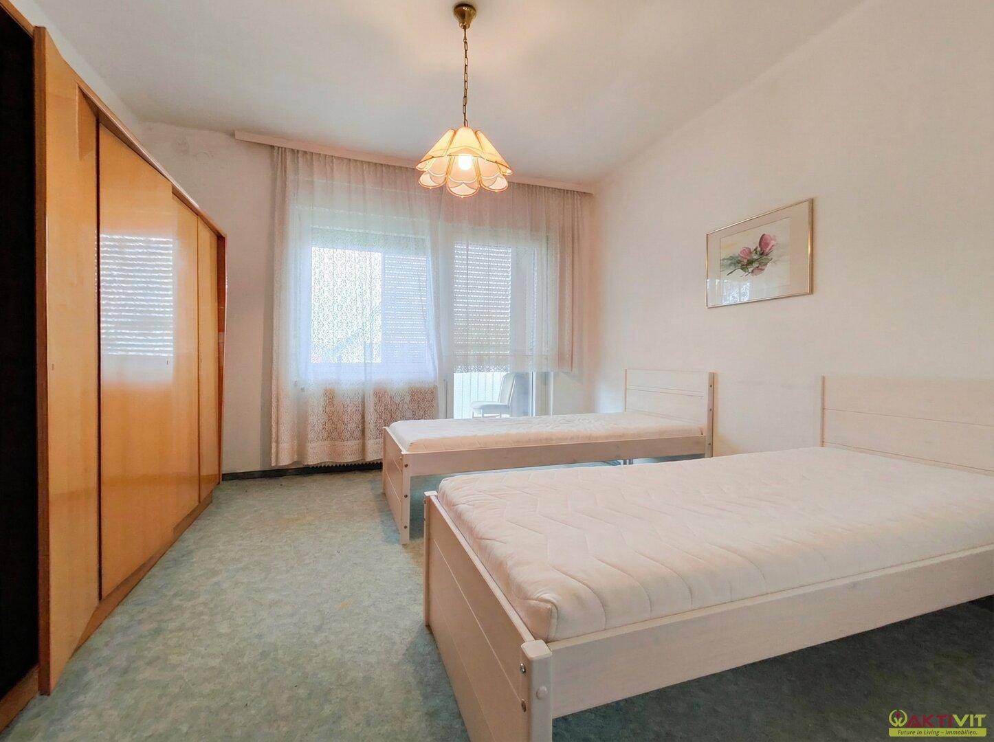 Schlafzimmer mit zwei Einzelbetten, Teppichboden und großem Kleiderschrank.