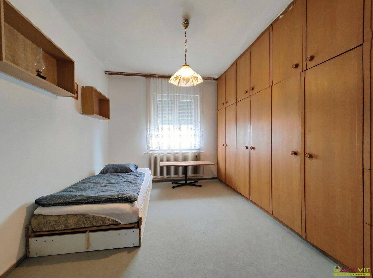 Schlafzimmer mit Einzelbett, Teppichboden und raumhohen Einbauschränken.