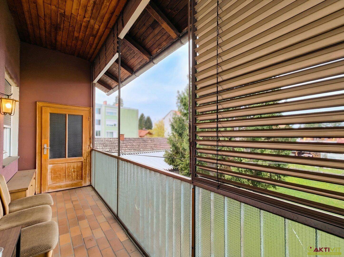 Überdachter Balkon mit Holzdecke und Blick auf die Umgebung.