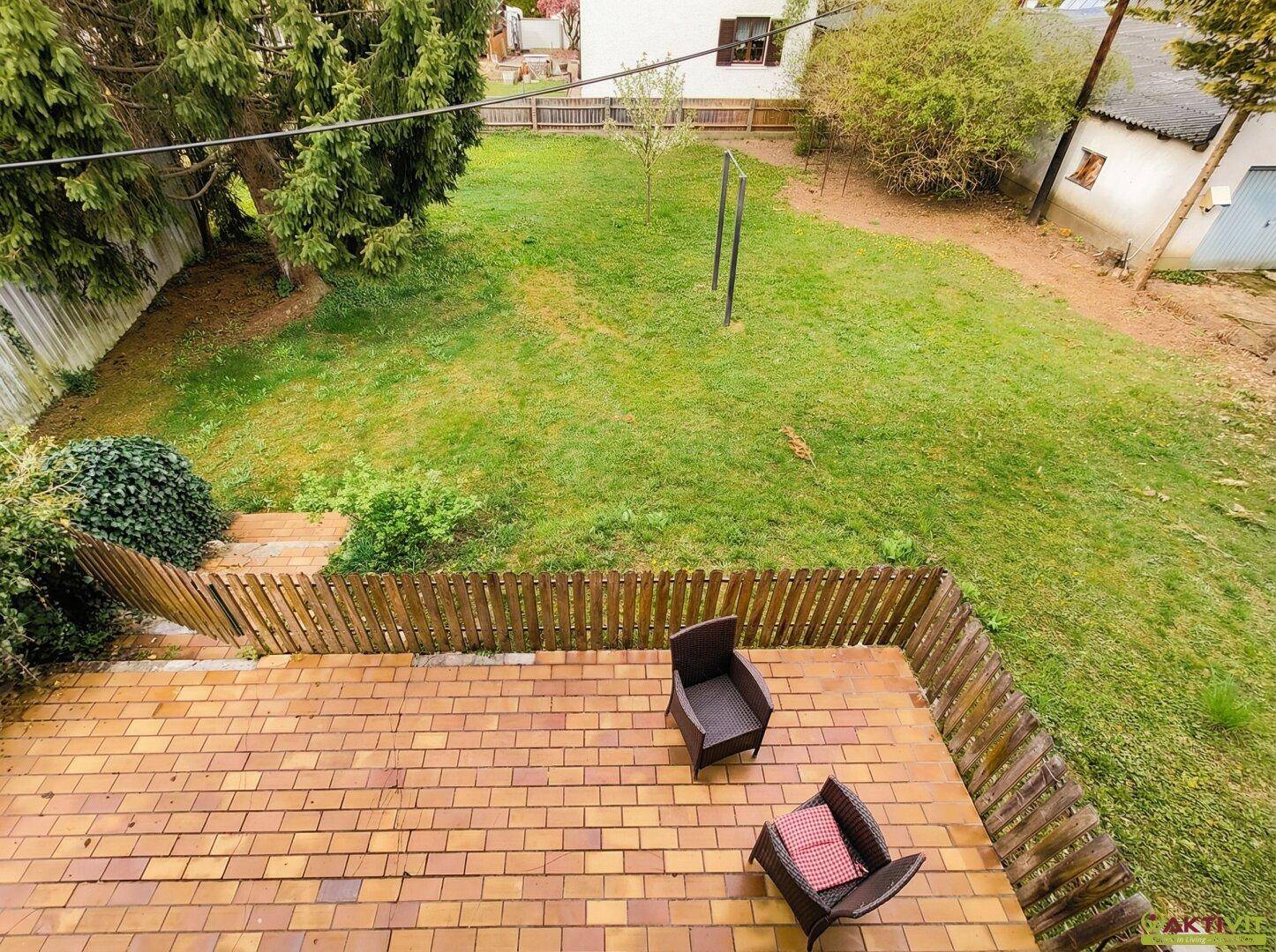 Blick von oben auf den großen Garten mit Rasenfläche und angrenzender Terrasse.