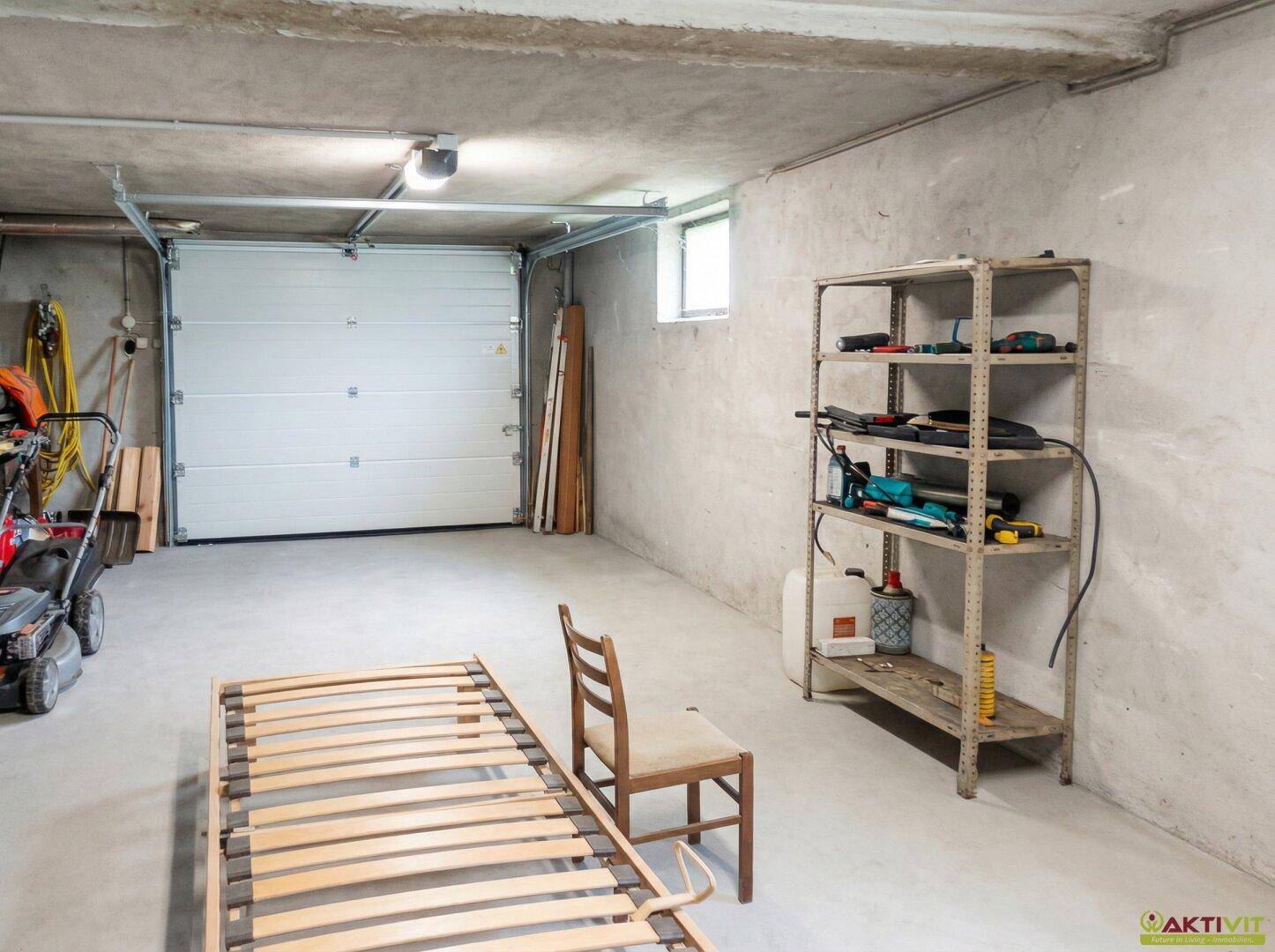 Geräumige Garage oder Abstellraum mit Betonboden und Rolltor.