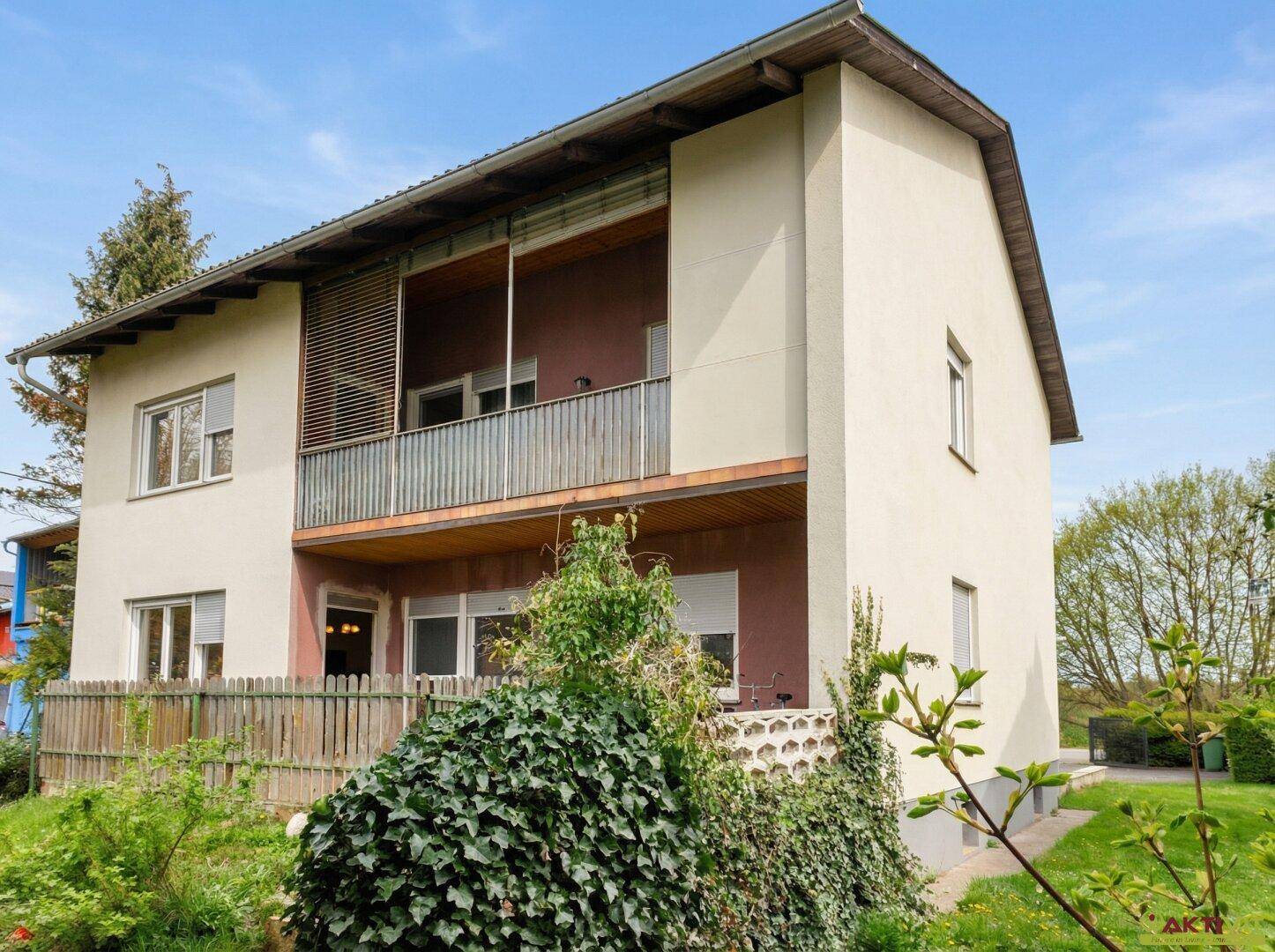 Seitenansicht des Hauses mit Balkonen und umgebender Bepflanzung.