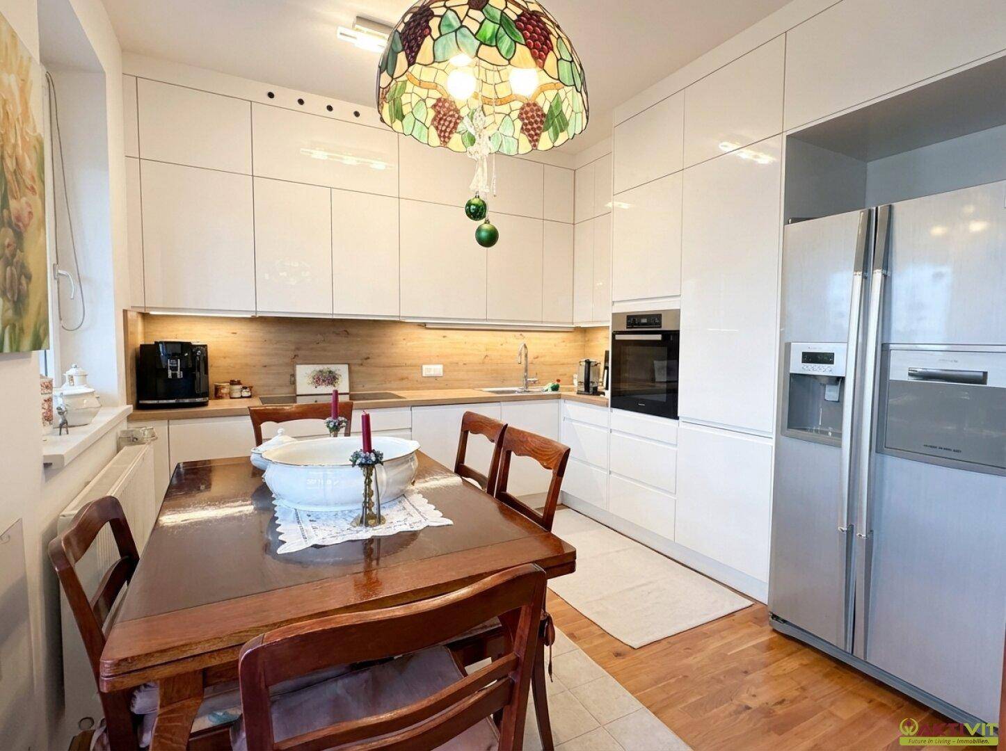 Helle, moderne Einbauküche mit Essbereich, weißen Schränken und großem Kühlschrank.