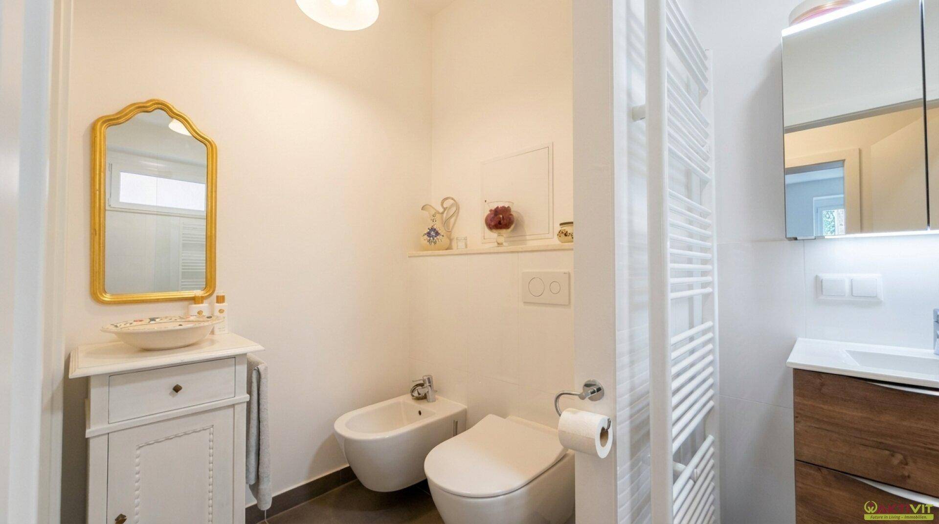 Separates WC mit Bidet, wandhängender Toilette und kleinem Waschtisch.