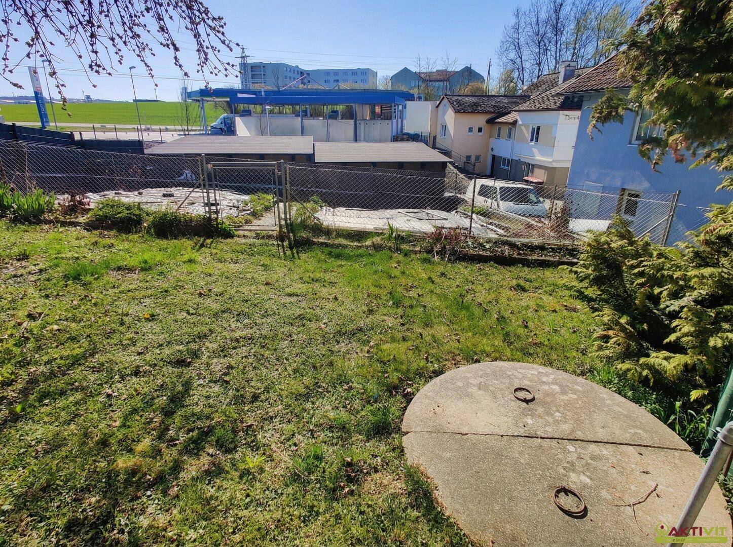 Grüner Gartenbereich mit einer Betonabdeckung und Blick auf die Umgebung.