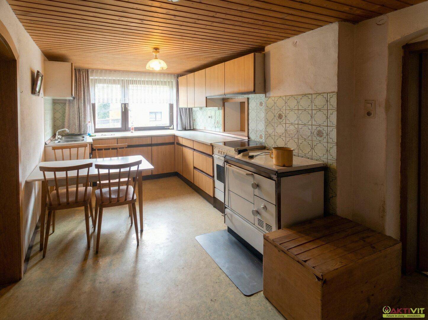 Traditionelle Küche mit Holzschränken, Essbereich und altem Herd.