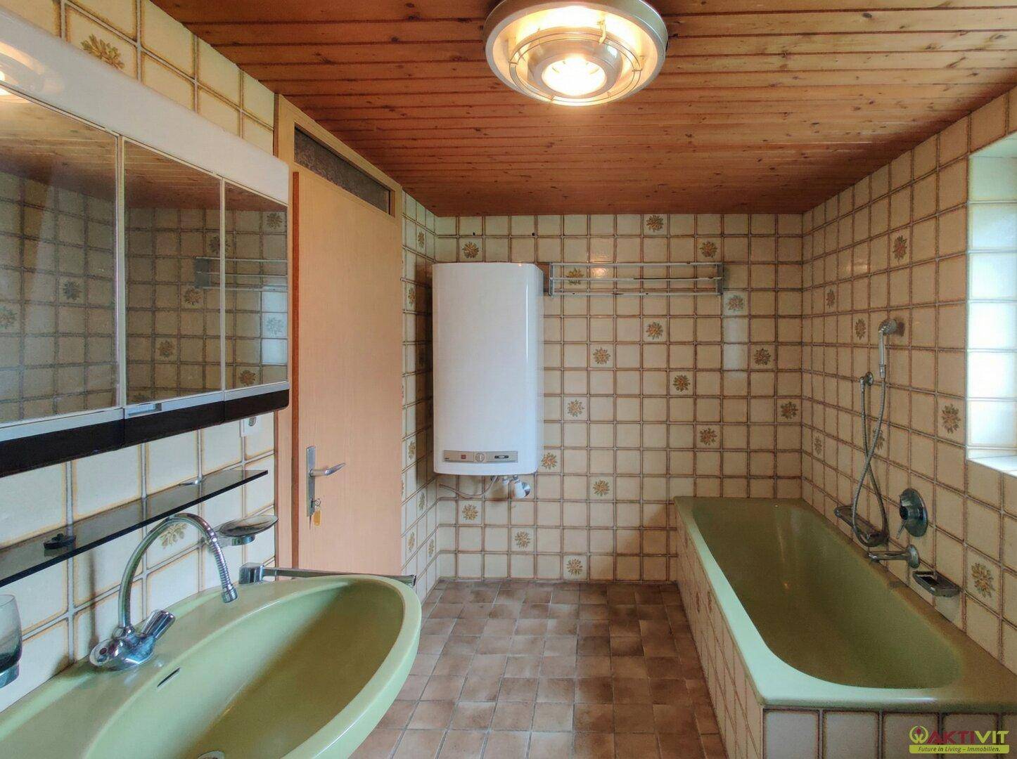 Badezimmer im Stil der 80er Jahre mit grüner Badewanne, Waschbecken und Holzdecke.
