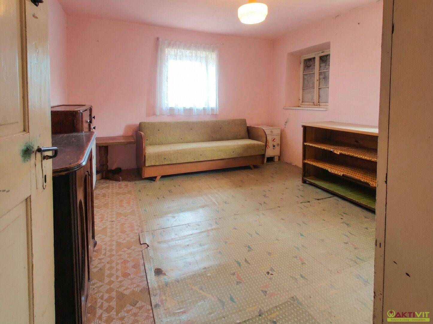 Helles Schlafzimmer mit rosa Wänden, Sofa und gemustertem Bodenbelag.